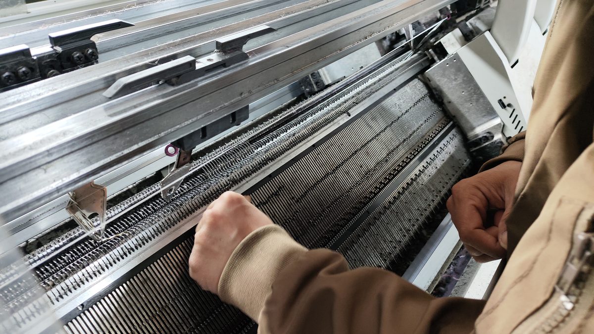 Operator working at a flat knitting machine