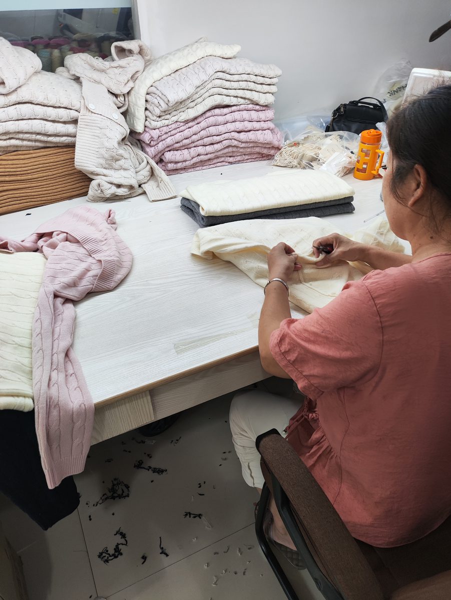Worker hand-finishing a sweater at the quality table